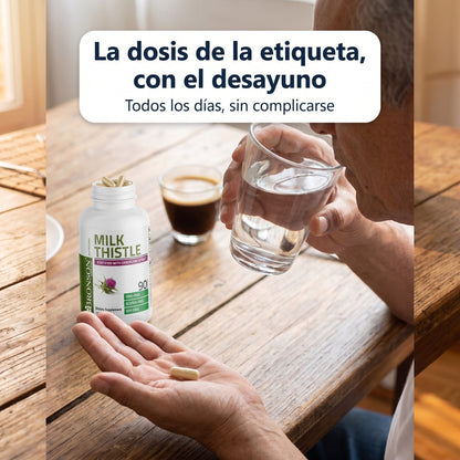 Cápsula de cardo mariano en la mano con un vaso de agua en el desayuno